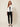 White Ag Bahar Coat on model - front view, white cropped satin jacket worn open over a black camisole, wide shawl collar and draped lapels with soft pointed front panels, sheer floral lace sleeves with solid white cuff bands