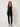 601570 BLACK FRINGE TOP - front view on model, draped cowl halter top with two-button tab and fringe hem, worn with black slim pants