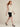 Cream sleeveless cowl-neck top on model, walking side view