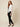 White Ag Bahar Coat on model - three-quarter view showing the open draped front over a black camisole and one sheer floral lace sleeve in profile