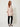 Pink Linen Bandi Coat on model - three-quarter view showing the closed gold zipper front, chest flap pocket and front waist bows