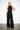 Endo Black Overall — front view on model showing the disc appliqué bodice, halter collar and sash belt
